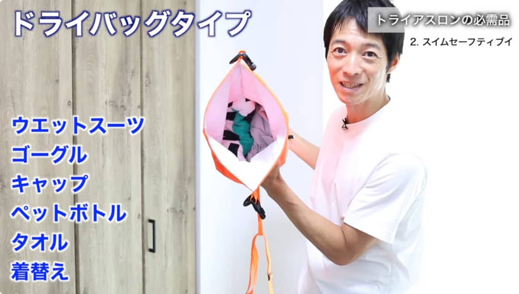 ZONE3 スイムセーフティブイ（ドライバッグタイプ）を開き、内部にウェットスーツやゴーグル、キャップ、タオルなどの収納例を示している様子